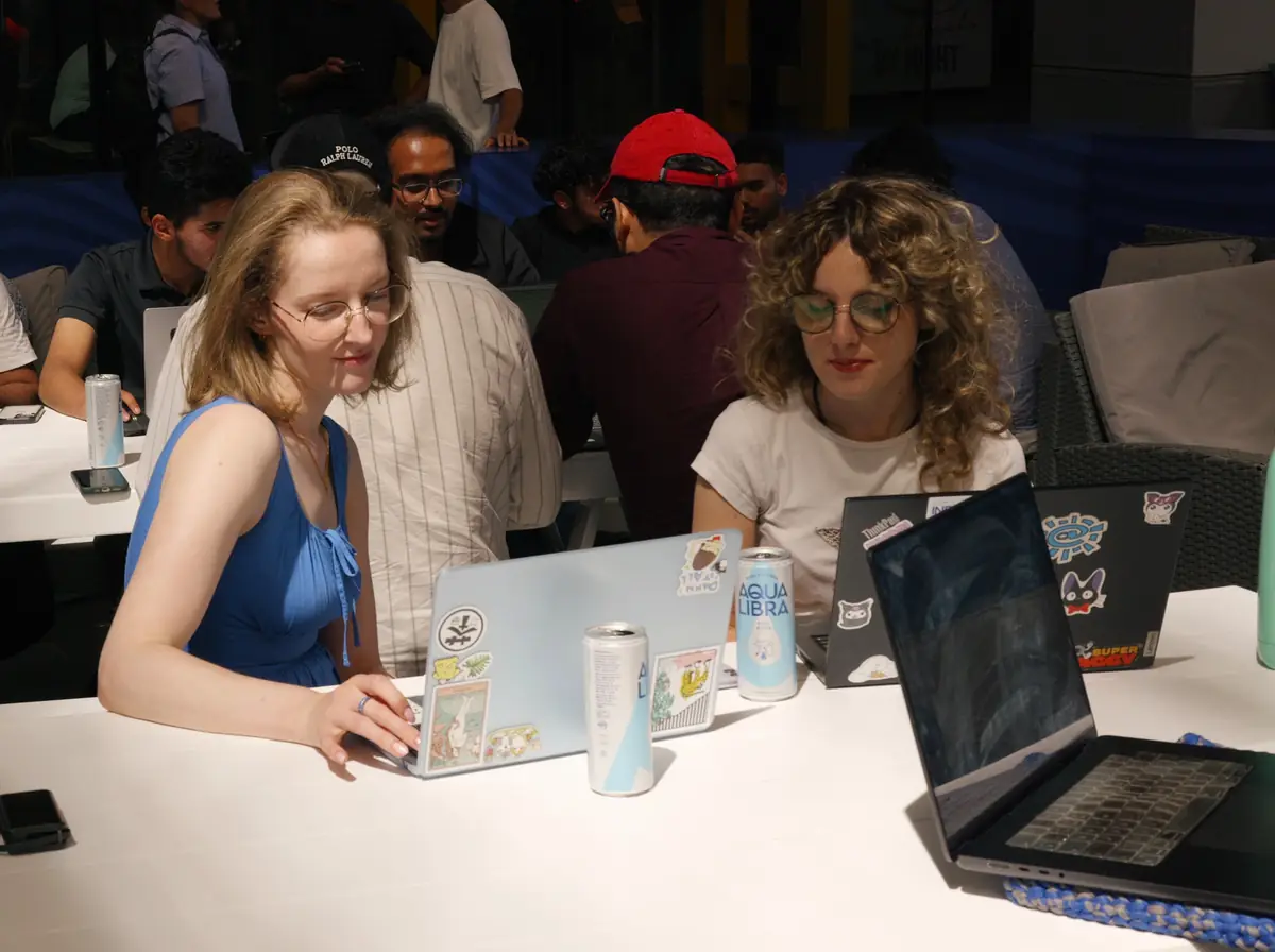 Two hackathon participants working on laptops